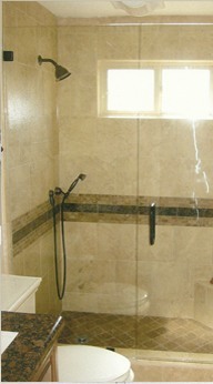 Glass shower door in a travertine bathroom, installed by JP Glass & Mirror